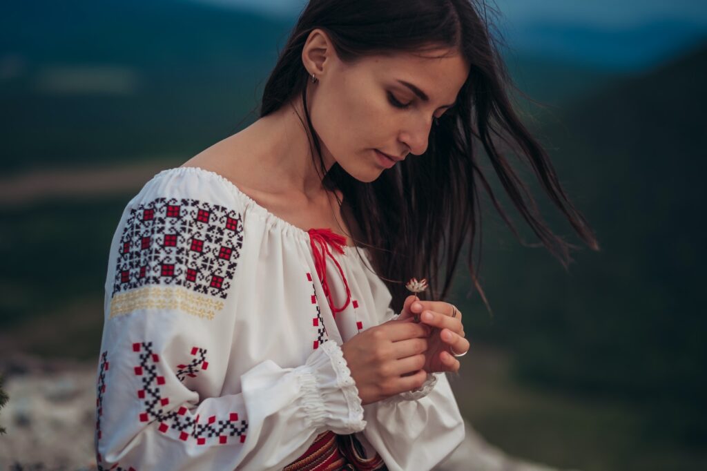 Atractive woman in traditional romanian costume on mountain green blurred background